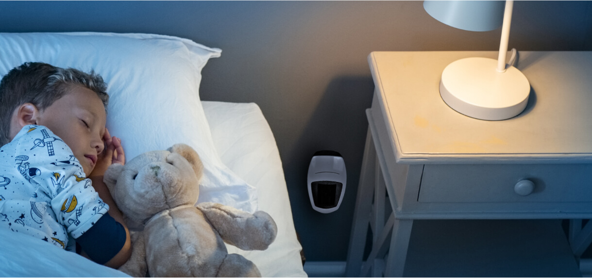 A bedroom scene with a small heater low on the wall near a nightstand.